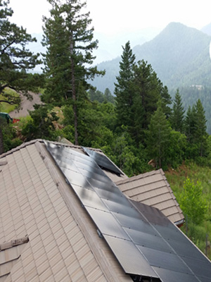 house with all black rooftop solar panels over looking the mountains