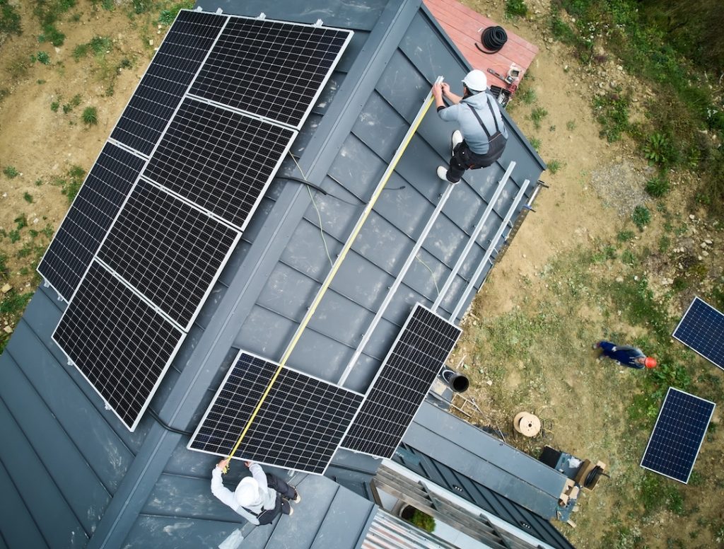 Solar installation crew installing solar panels on roof of home
